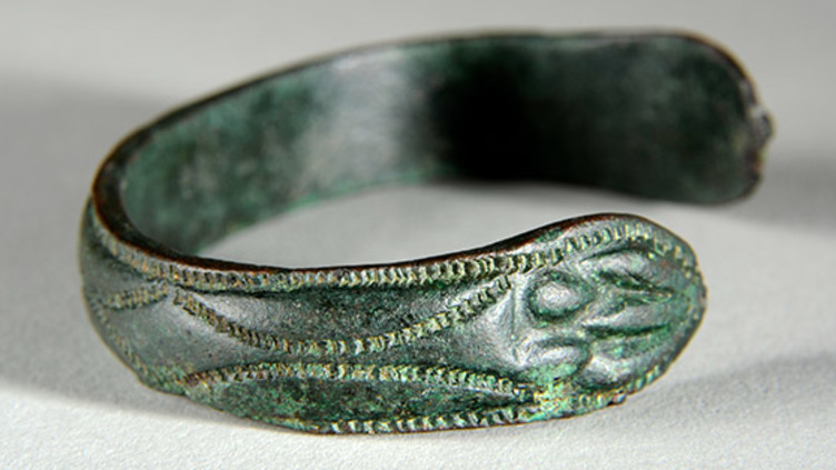 A metal bracelet with decorations carved into it