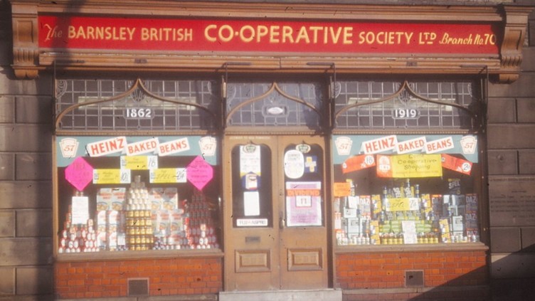 Shopfront with window display of stacked goods and Heinz Baked Beans window stickers