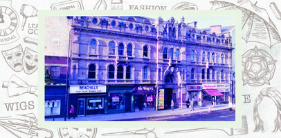 Entrance to Civic Hall with a yellow vertical poster advertising events. Shopfronts for Beachills, an unnamed green fronted shop with a mega sale poster, Mr Wayne, Singer, Charlesworth and Barnsley Civic box office.