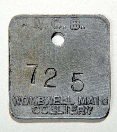 A square shaped pit check with text N.C.B 725 and Wombwell Main Colliery