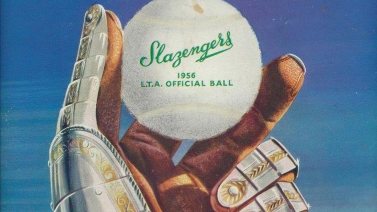 A close up of a hand wearing a brown and white glove holding a white ball with 'Slazengers 1956 L.T.A official ball' on it