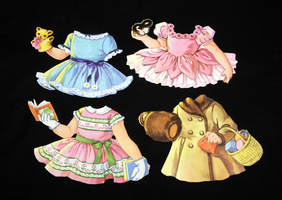 Four vintage paper doll dresses are displayed on a black background. The outfits include a blue dress with a teddy bear, a pink ballet outfit, a green and pink dress with a book, and a tan coat with a basket.