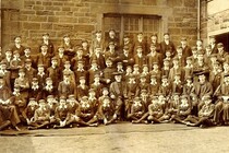 Group of school children posing for a photo in a yard.