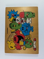 Wooden puzzle board featuring colorful cartoon characters with various expressions and costumes. Each character has a small red knob for easy handling. The board has a light brown background with black printed outlines.