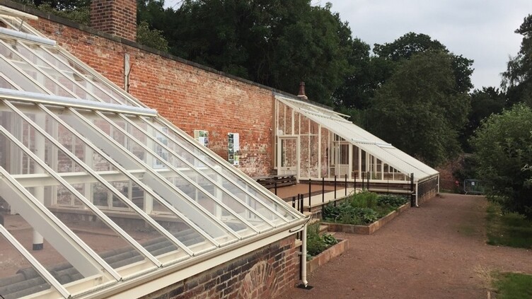 Two conservatories adjoining a brick building with gravel path between