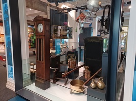 Experience Barnsley Museum main gallery. A display with a grandfather clock, copper pans and a small wooden rocking chair