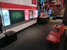 Football display showing an interactive screen and two red football stadium chairs facing it