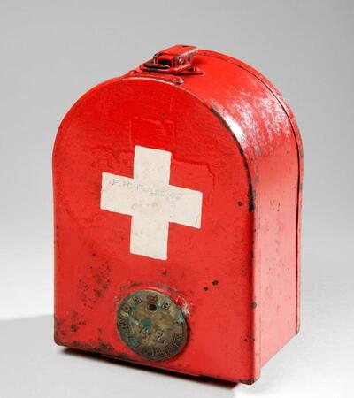 A red first aid tin with a white cross on the front
