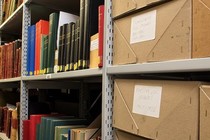 Shelves containing books and boxes of archives
