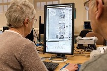 Two customers in Barnsley Archives looking a digital newspaper on a monitor